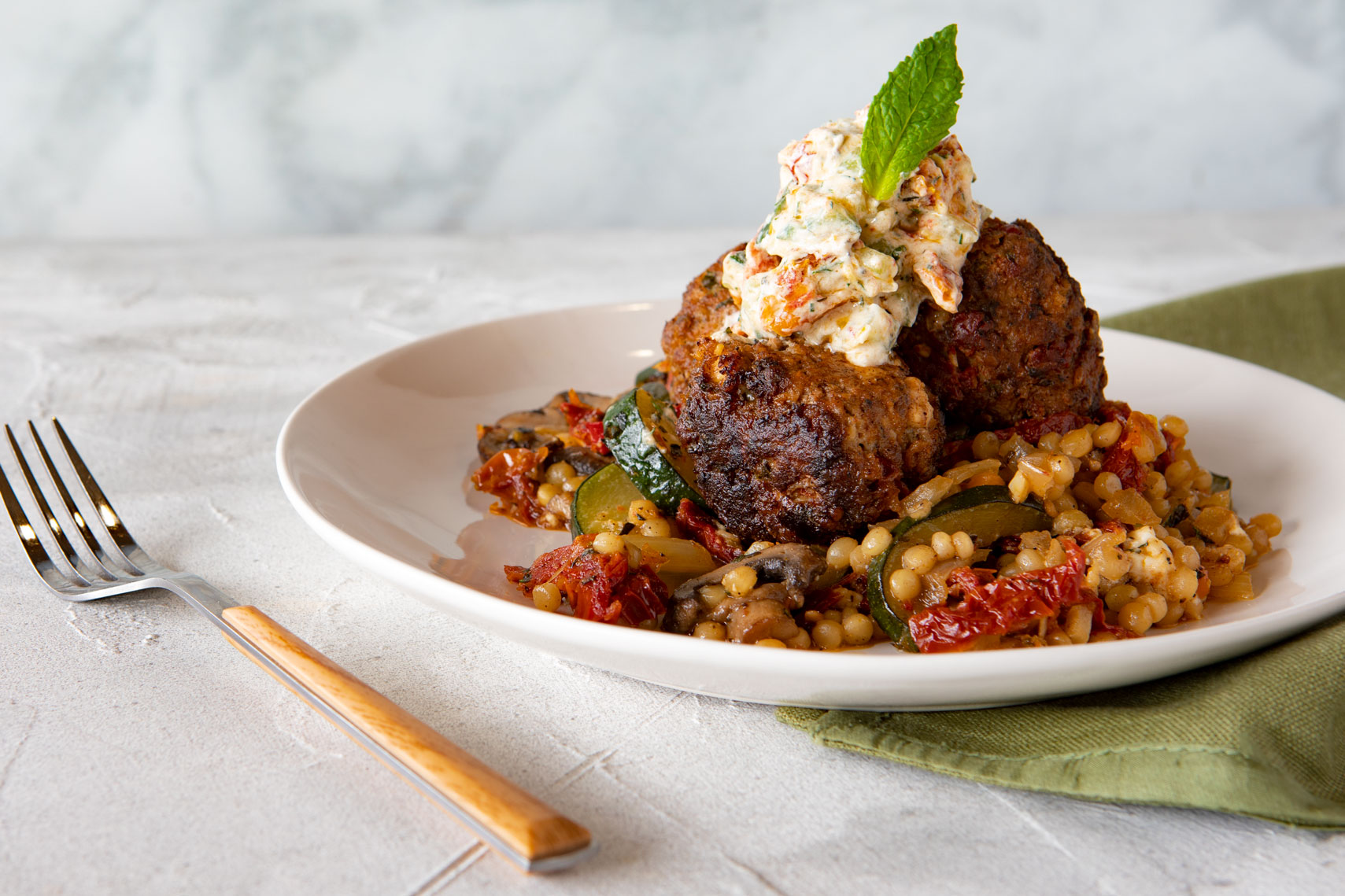  Mediterranean Lamb Meatballs over Pearl Couscous Veggie Melange with Sun Dried Tomato Tzatziki